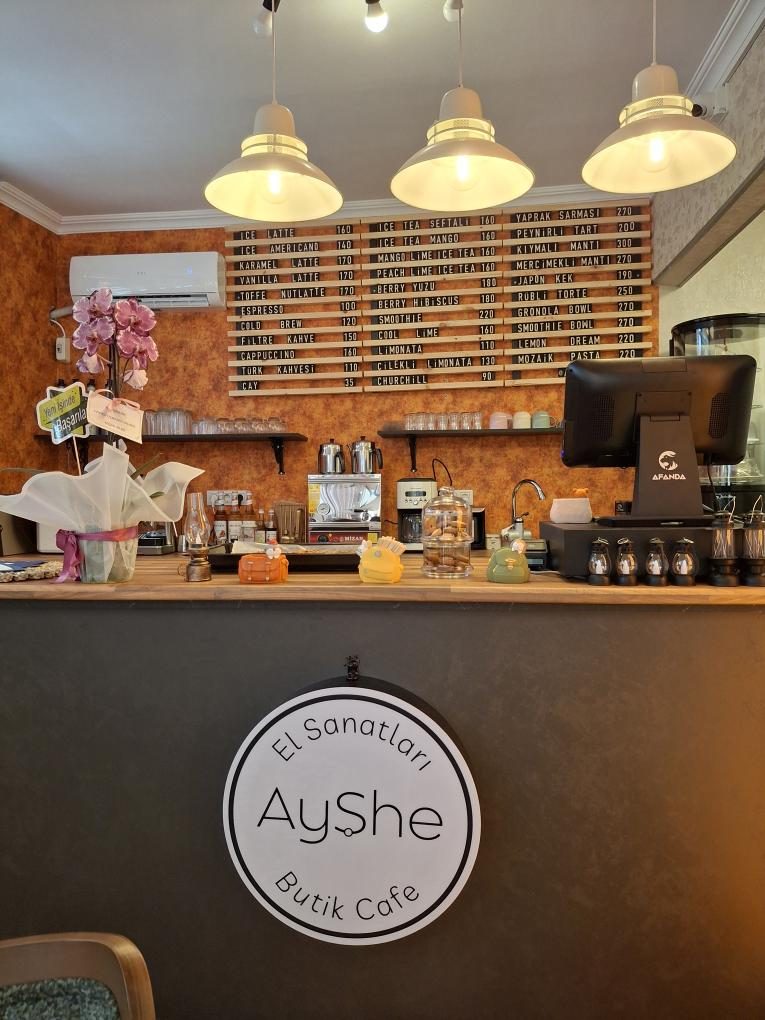 Ayşe El Sanatları Butik Cafe'de üç panolu ahşap harf panosu, sıcak sarkıt aydınlatma altında
