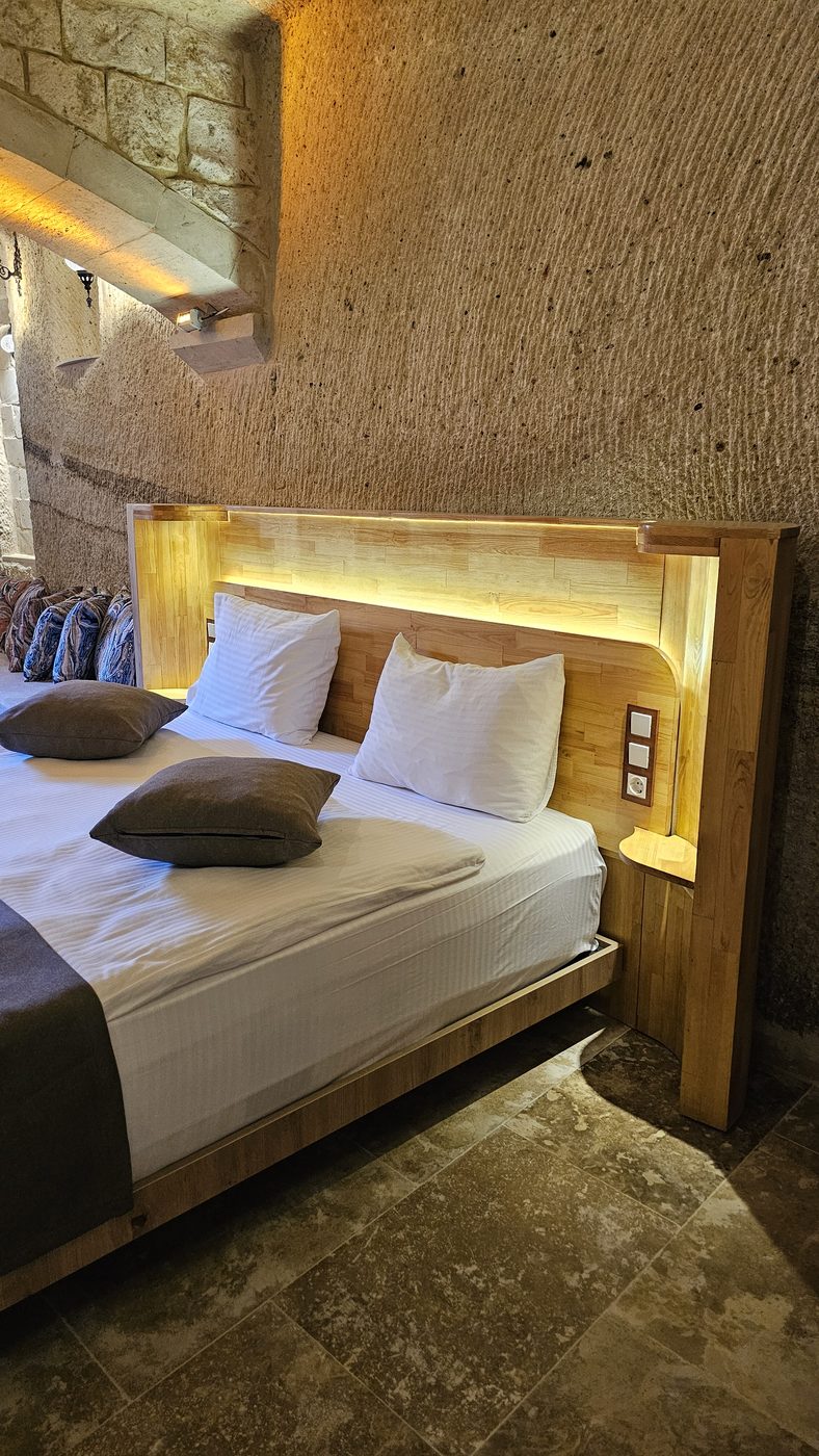 Solid pine furniture in Göreme: carved wooden headboard with LED lighting against a stone wall