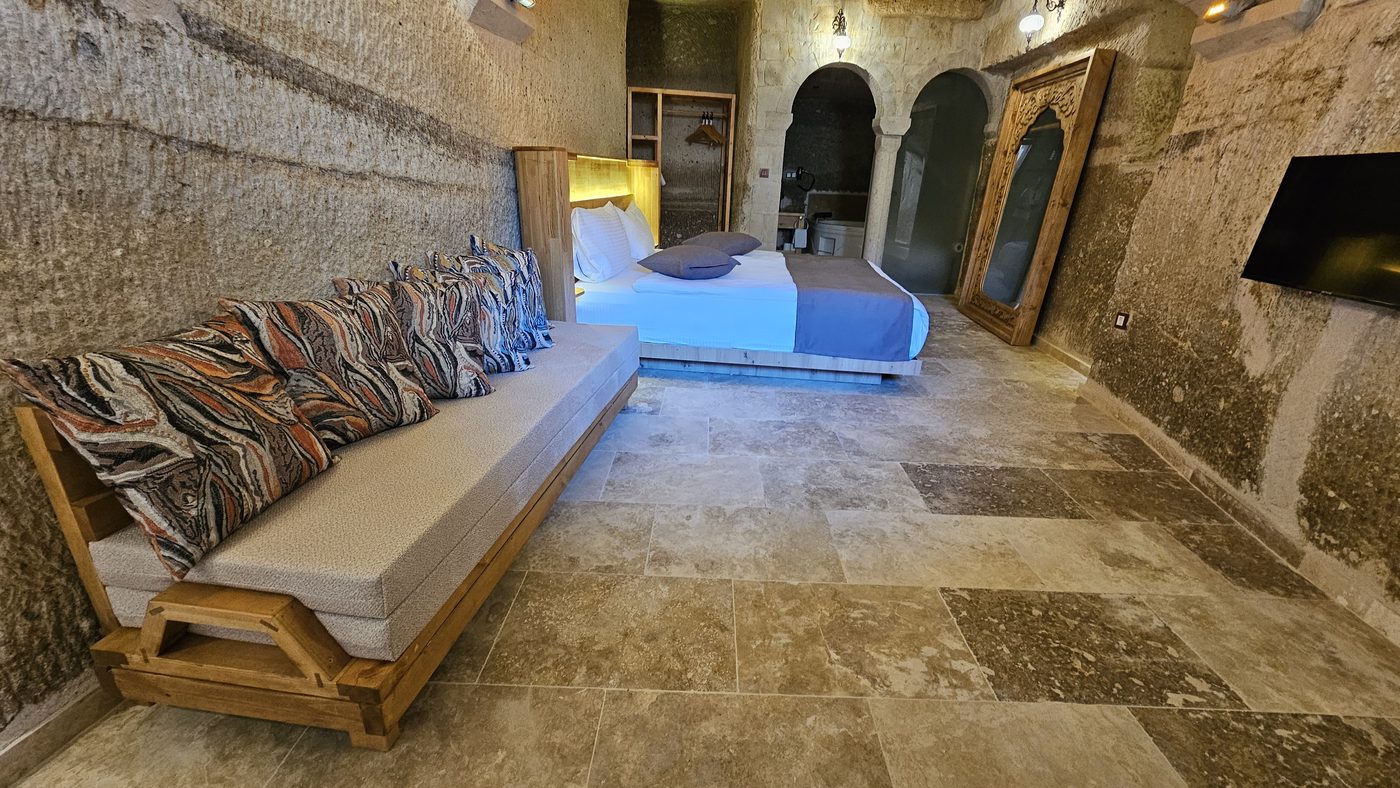 Solid wood cave hotel furniture in a Göreme hotel room: convertible daybed, LED headboard and carved mirror