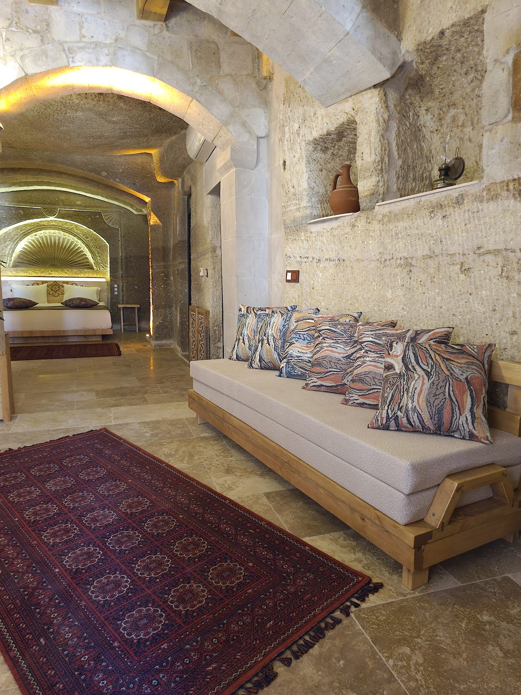 Carved wooden headboard detail in a Cappadocia cave hotel atrium, next to a carved stone niche