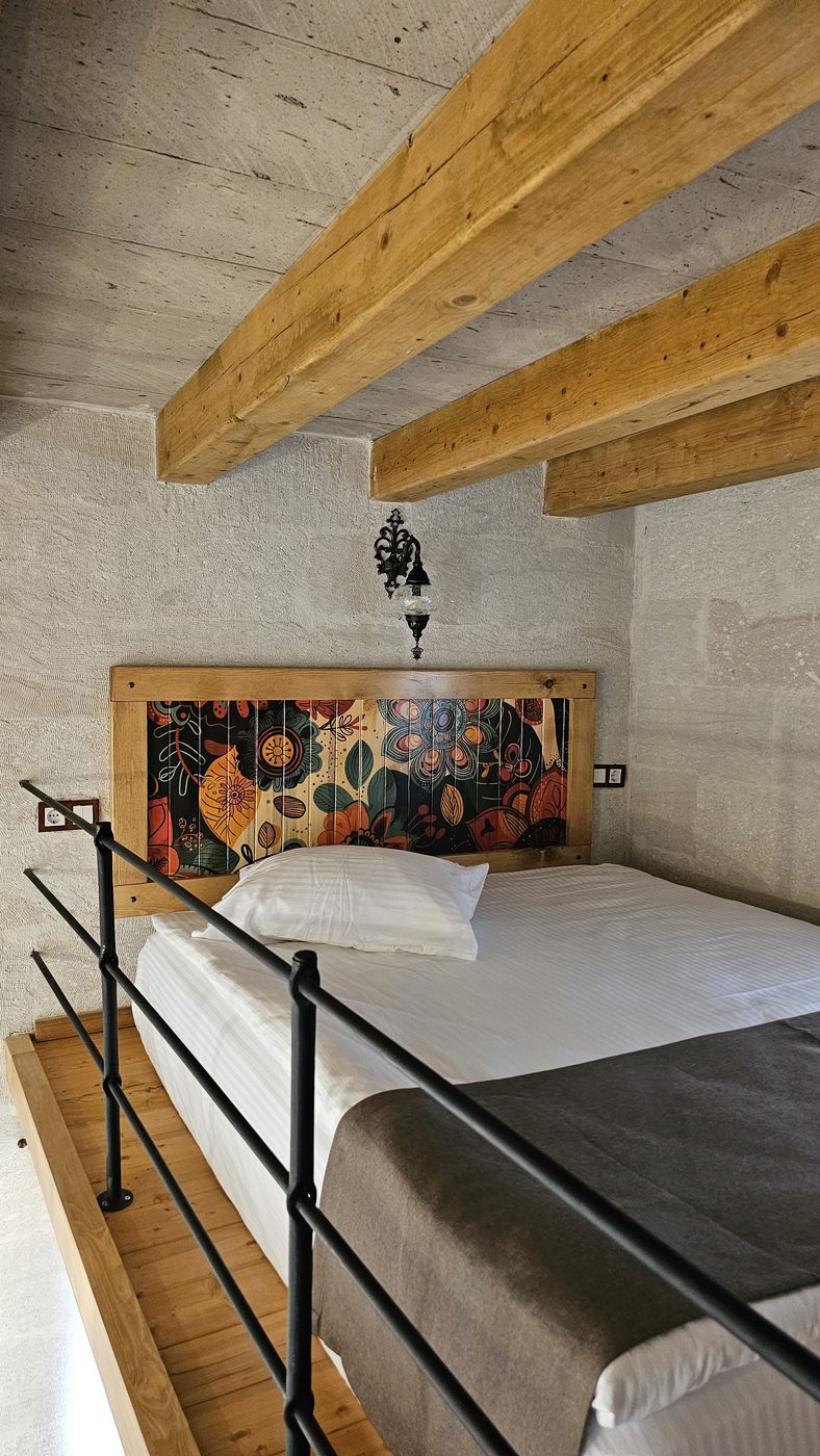 Cave hotel room decoration in Göreme: exposed wooden ceiling beams and an iron railing in a loft area