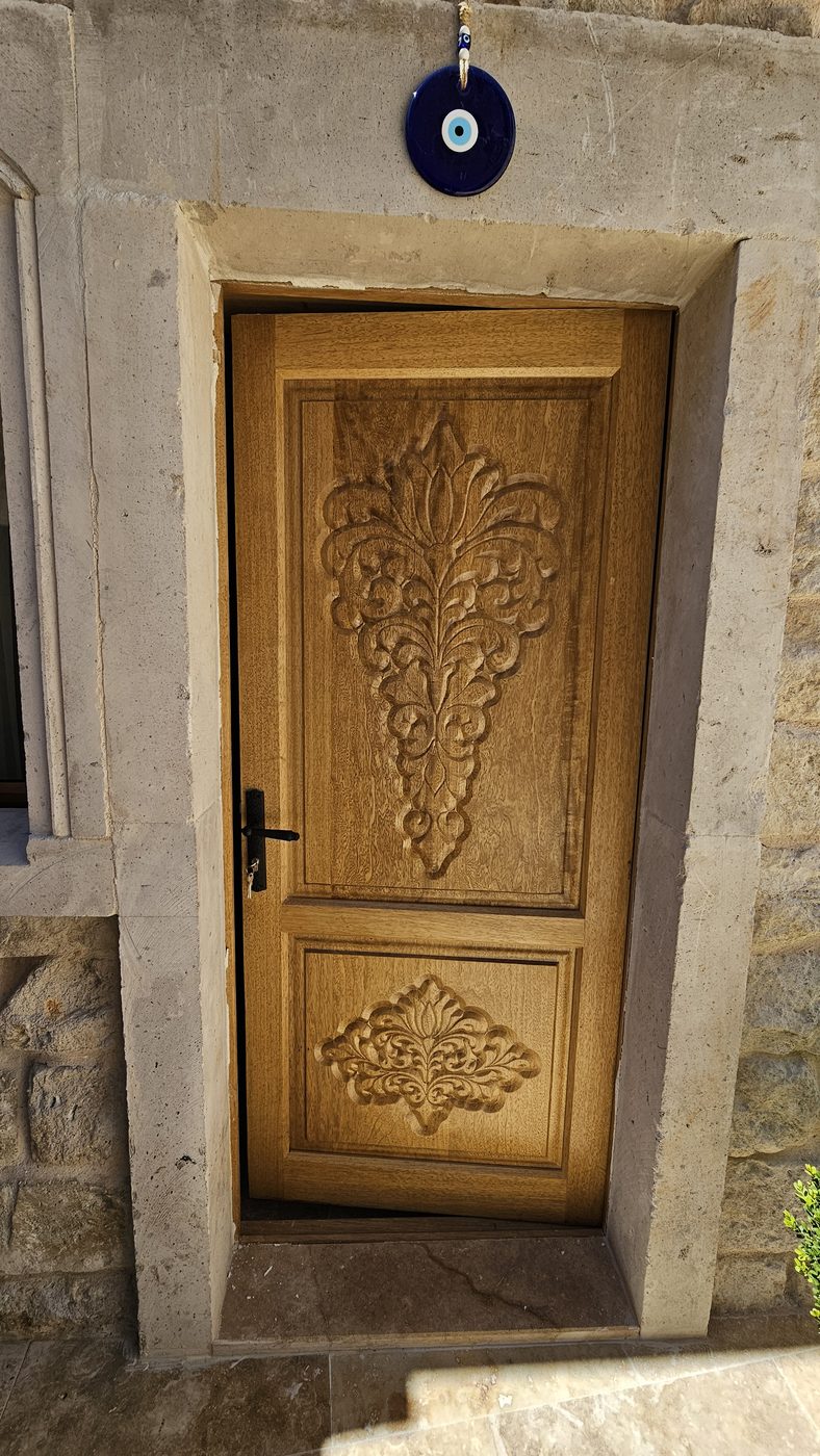 Carved wooden entrance door with a flower motif, cave hotel furniture in imported limba wood