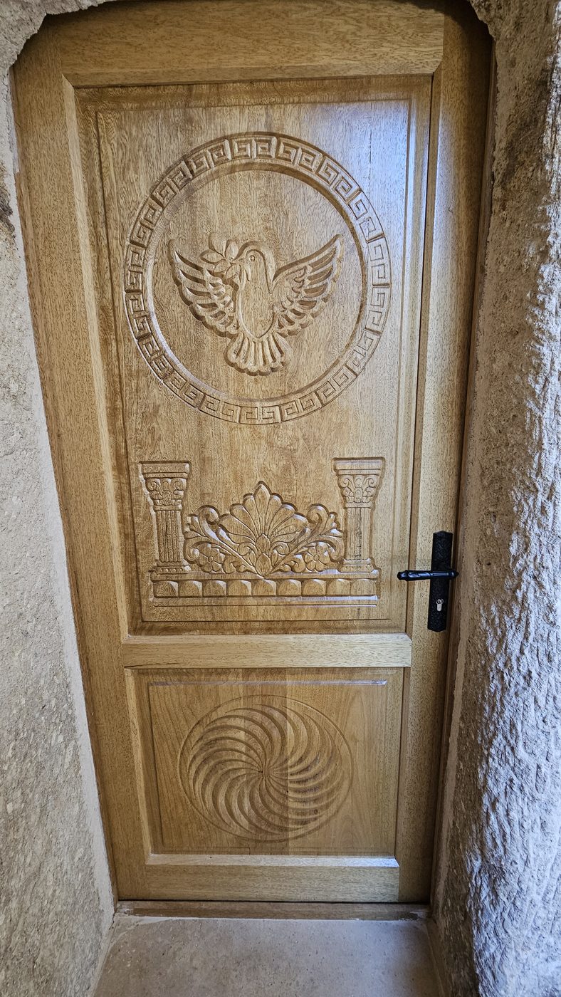 Carved wooden entrance door with a bird motif, solid pine furniture for a Göreme cave hotel