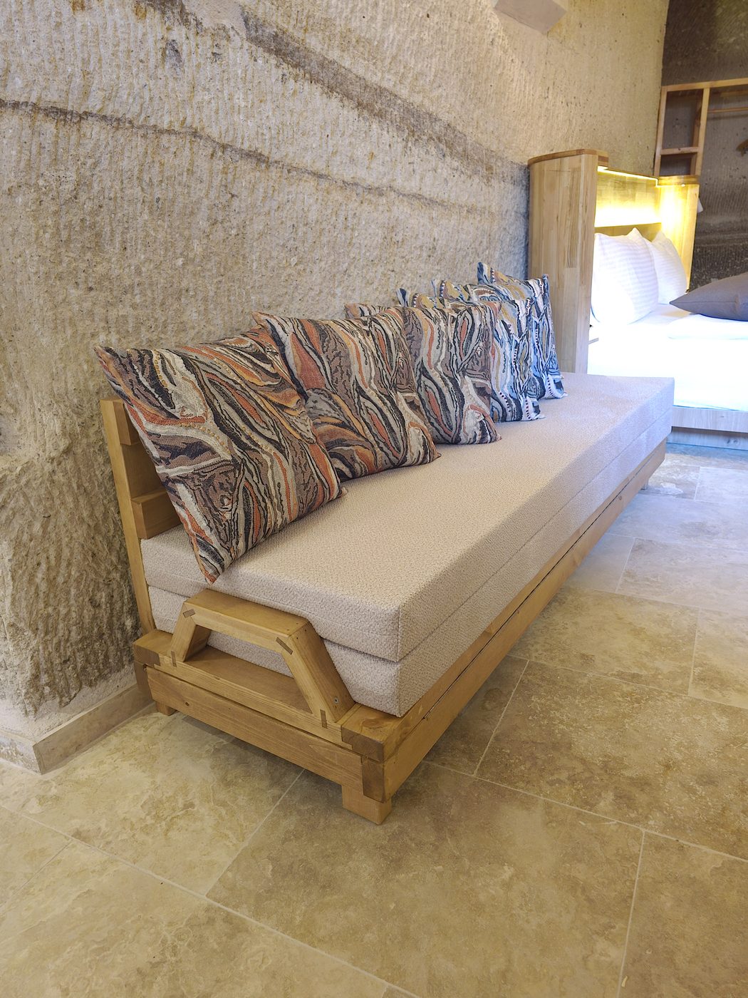 Solid wood convertible daybed bench in a Göreme cave hotel room, opening into a single bed